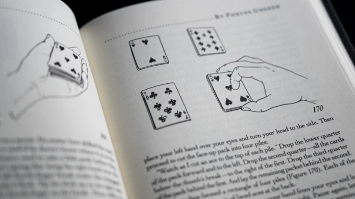 Hardcover book titled "By Forces Unseen", a magic instructional guide by Ernest Carrick, written by Stephen Minch open to show illustrations
