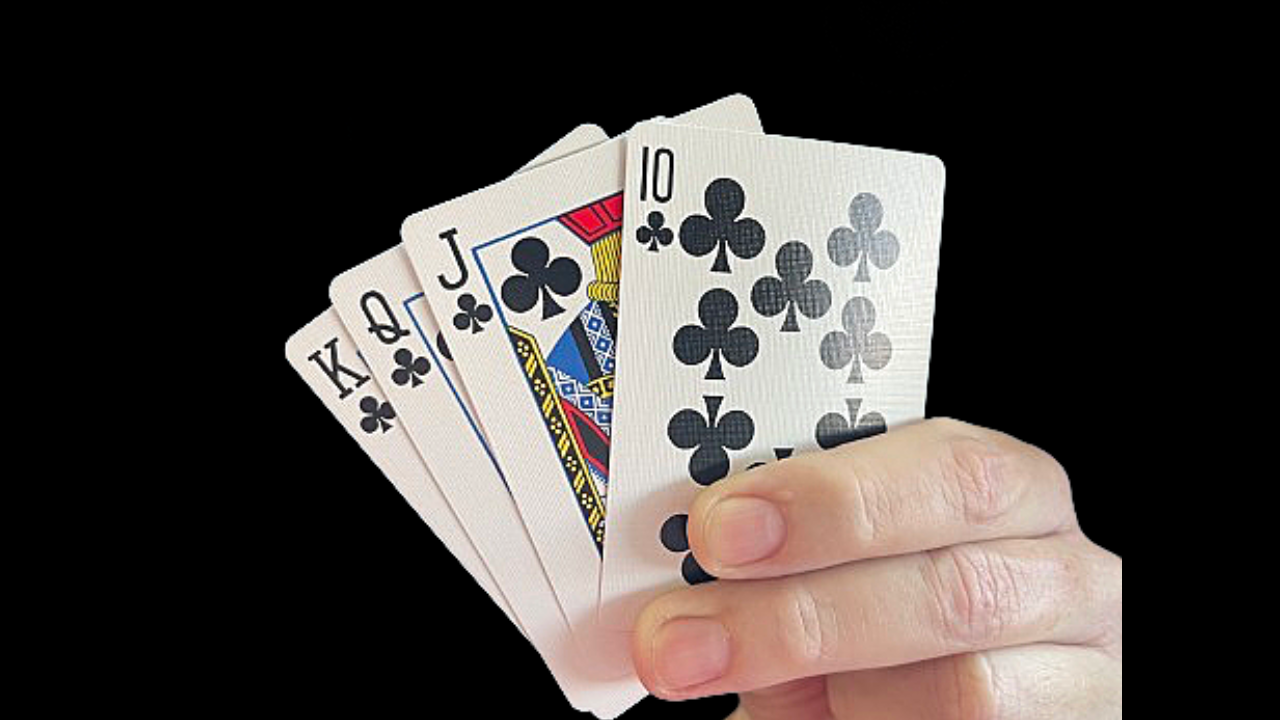 Hand holding four playing cards, showing a 10, Jack, Queen, and King of Clubs