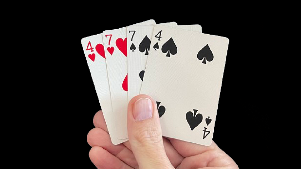 Hand holding four playing cards fanned out