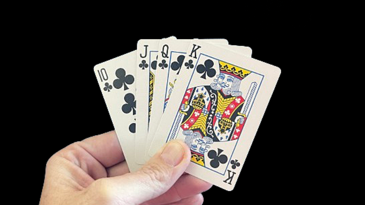 Hand holding four playing cards, showing a 10, Jack, Queen, and King of Clubs