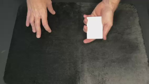 Hands holding blank faced cards about to perform the blank wild card magic trick against a black background