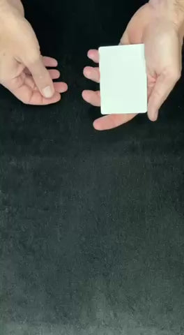 Hands holding blank faced cards about to perform the blank wild card magic trick against a black background