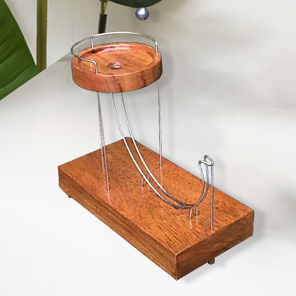 Wooden ball-launching toy with two metal ramps and a circular wooden platform on a counter top.
