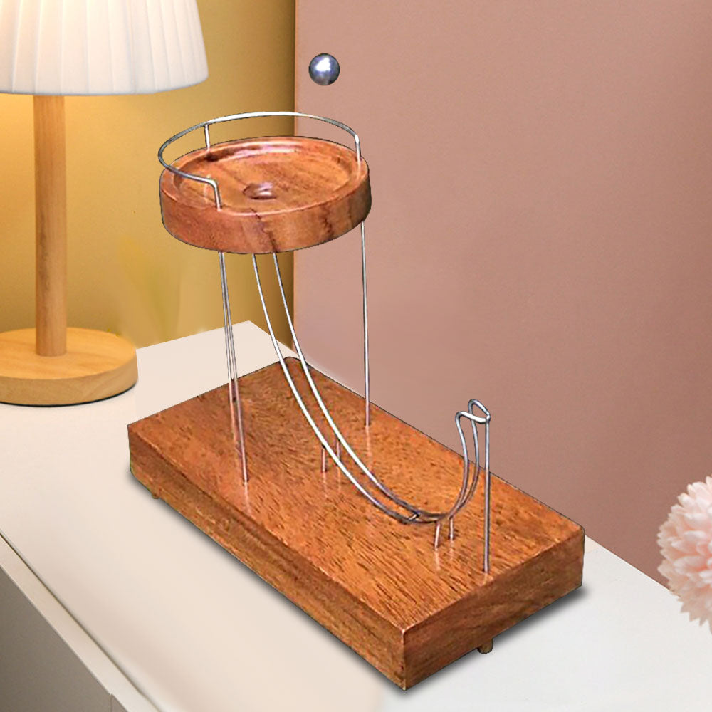 Wooden ball-launching toy with two metal ramps and a circular wooden platform next to a lamp.