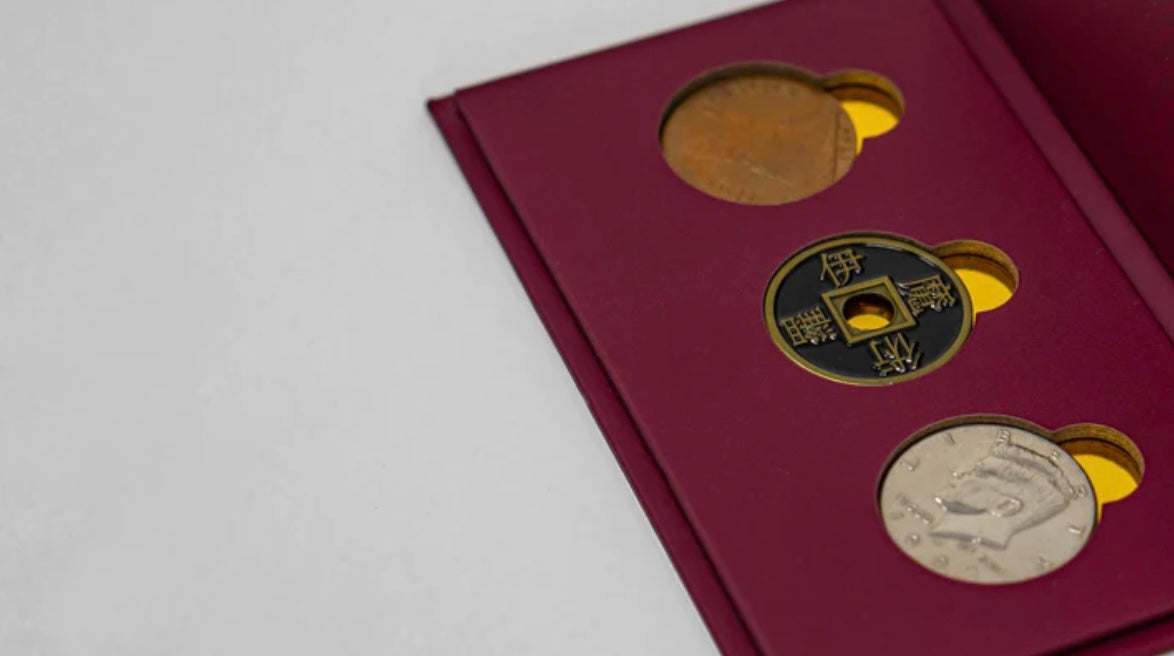 Three coins displayed in a case used in the magic trick copper, brass, and silver coins in a maroon case.