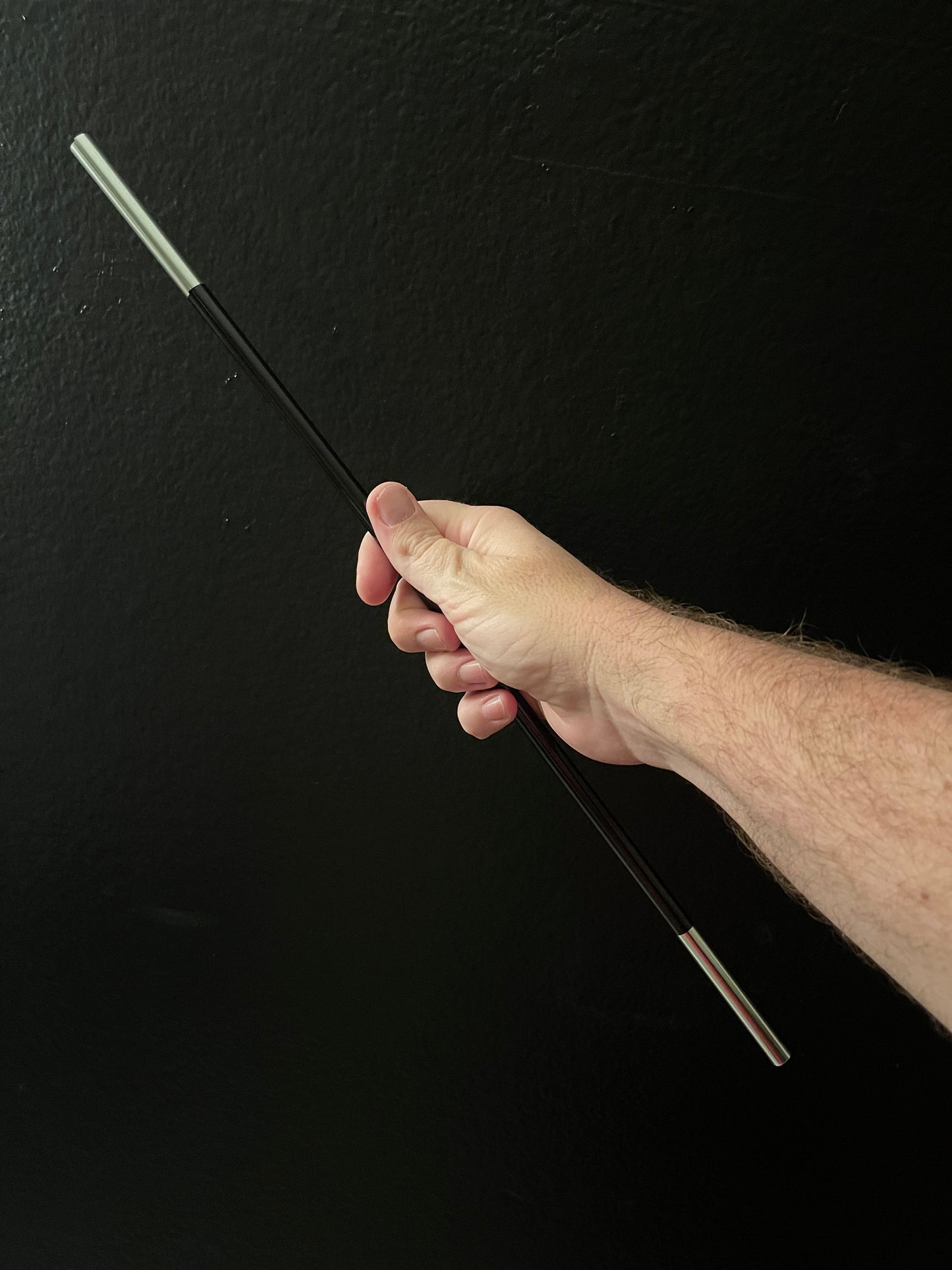 Hand holding the appearing magic wand magic trick against a black background