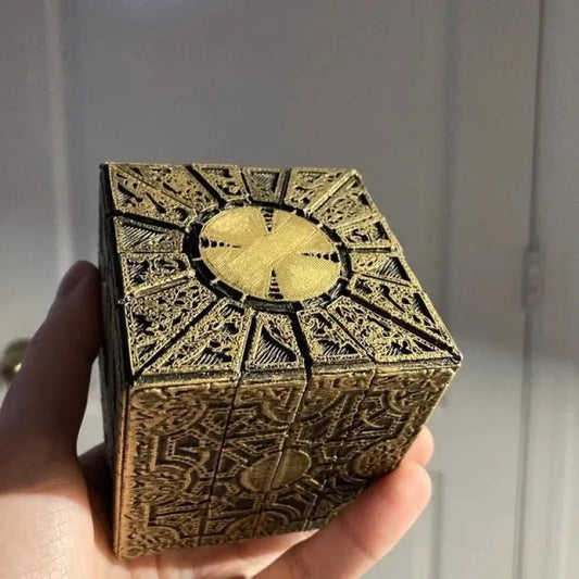 gold-toned box with intricate, ornate, symbolic design reminiscent of the "The Box" from the movie Hellraiser.
