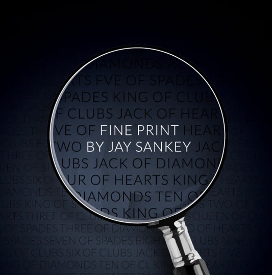 Magnifying glass focused on a dense list of playing cards, including "Fine Print" by Jay Sankey.