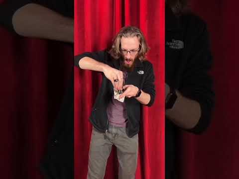 Close-up of a magic trick demonstrating a playing card and a dollar bill, manipulated with a chapstick penetrating a dollar bill short video